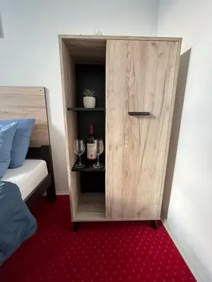 a cupboard with wine glasses and wine bottles in a bedroom at Stari Zaječar apartments in Zaječar