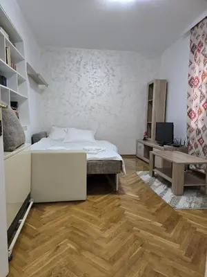 a white bedroom with a bed and a table at Apartman Stefanovic in Vrnjačka Banja