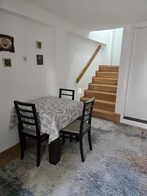 a table and two chairs in a room with stairs at Apartman Stefanovic in Vrnjačka Banja
