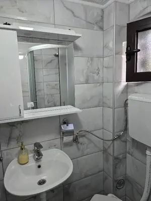 a white bathroom with a sink and a mirror at Apartman Stefanovic in Vrnjačka Banja