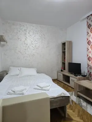 a white bedroom with a bed and a tv at Apartman Stefanovic in Vrnjačka Banja