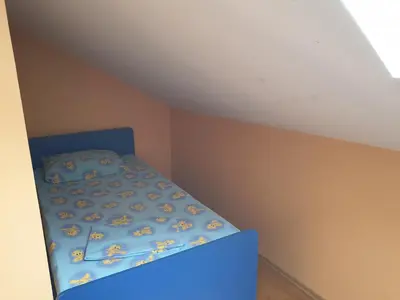 a small bedroom with a blue bed in a attic at Apartmani Mile in Soko Banja