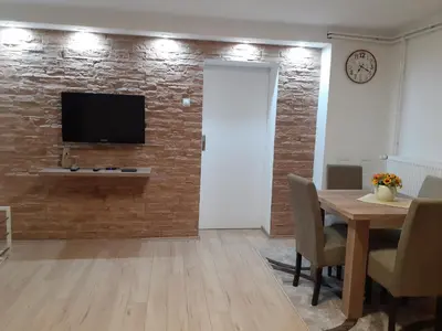 a living room with a wooden table and a television on a brick wall at Apartman Nena in Pirot