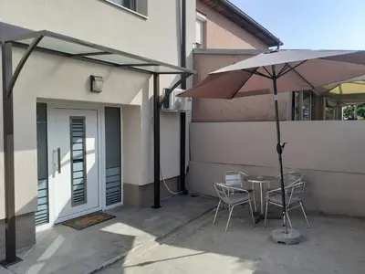 a table and chairs with an umbrella next to a building at Apartman Nena in Pirot