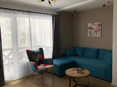 a living room with a blue couch and a table at Apartman Srebrna pahulja in Kopaonik