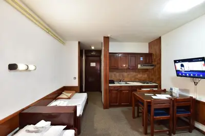 a room with two beds and a kitchen with a tv at Apartments JAT Kopaonik in Kopaonik