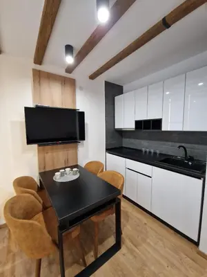 a kitchen with white cabinets and a black table and chairs at Apartments JAT Kopaonik in Kopaonik