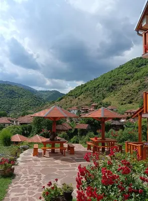 a patio with benches and umbrellas with mountains in the background at Kuca Stojanovica Topli Do in Pirot