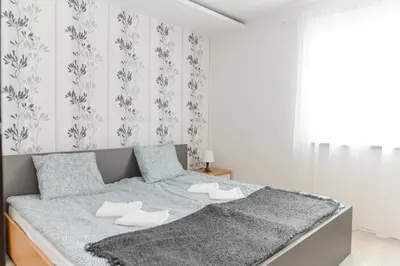 a white bedroom with a bed with a gray blanket at Panorama Lux in Soko Banja