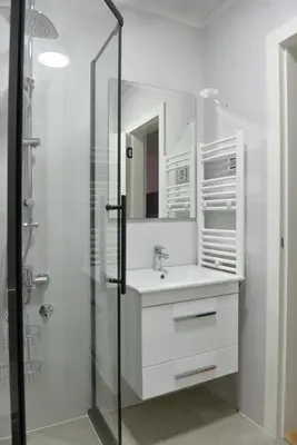 a white bathroom with a sink and a shower at 9 apartments in Jagodina