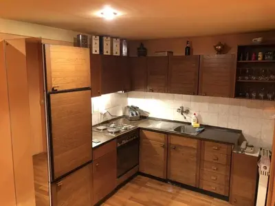 a kitchen with wooden cabinets and a stainless steel refrigerator at Loli Caffe Apartment in Prokuplje