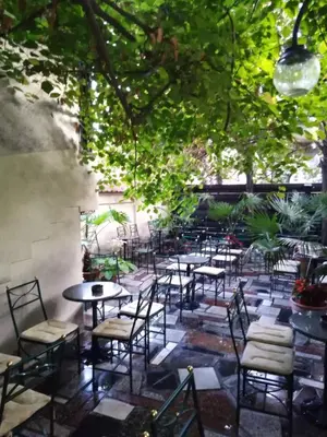 a group of tables and chairs in a patio with trees at Loli Caffe Apartment in Prokuplje