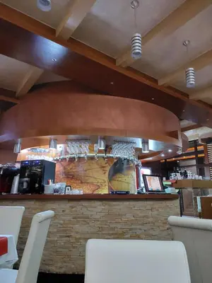 a bar in a restaurant with white tables and chairs at Mila apartmani Kopaonik in Kopaonik