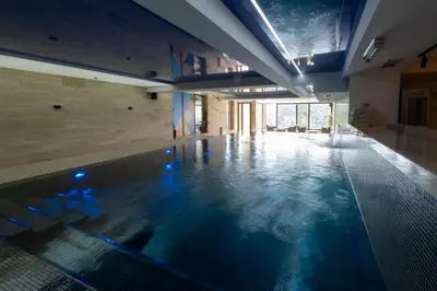 a large swimming pool with blue water in a building at Mila apartmani Kopaonik in Kopaonik