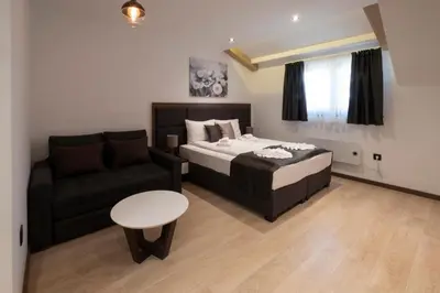 a bedroom with a bed and a couch and a table at Mila apartmani Kopaonik in Kopaonik