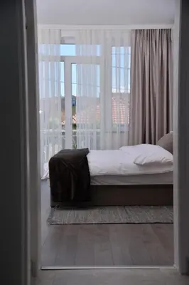 a bed in a room with a large window at Apartmani Milovanović in Vrnjačka Banja