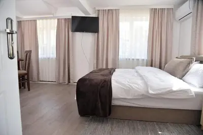 a bedroom with a bed with white sheets and curtains at Apartmani Milovanović in Vrnjačka Banja