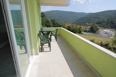 a balcony with a table and chairs and mountains at Bovan GREEN LAKE apartments in Soko Banja