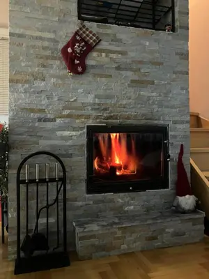 a fireplace with a stone wall at Zoara apartment in Kopaonik