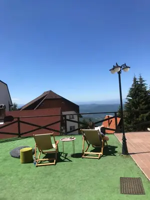 a person sitting in lawn chairs on a roof at Zoara apartment in Kopaonik