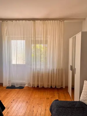a bedroom with a large window with white curtains at Apartman Lili in Soko Banja