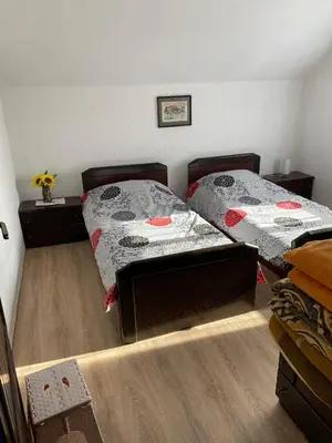 two twin beds in a room with wooden floors at Mićin dom in Pirot
