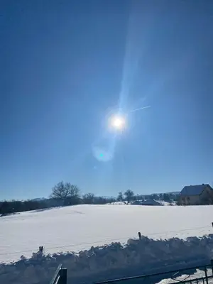 a snow covered field with the sun in the sky at Vikendica Matić in Goč
