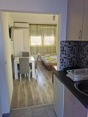 a kitchen and living room with a table and a dining room at Apartmani Manila, Vrnjačke terme-popust, SPA centar Pegaz-popust, garažno mesto in Vrnjačka Banja