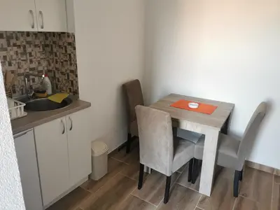 a small kitchen with a table with chairs and a sink at Apartmani Manila, Vrnjačke terme-popust, SPA centar Pegaz-popust, garažno mesto in Vrnjačka Banja