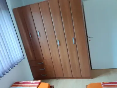 a dressing room with brown cabinets and a mirror at Apartman Andjela in Soko Banja