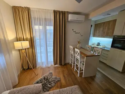 a living room with a kitchen and a table with chairs at Apartman Emma Vrnjačka Banja in Vrnjačka Banja
