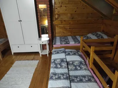 two beds in a room with wooden walls at Vikendica Darija in Kraljevo