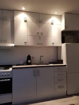 a kitchen with white cabinets and a sink and a refrigerator at FARAON pn 1 in Paraćin