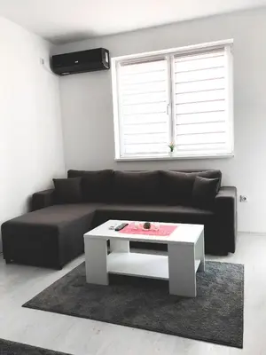 a living room with a black couch and a white coffee table at Apartman DEA in Soko Banja