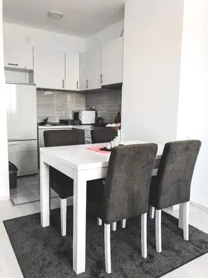 a kitchen with a white table and black chairs at Apartman DEA in Soko Banja