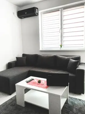 a living room with a black couch and a table at Apartman DEA in Soko Banja