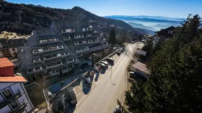 a city street with a building and cars parked on the road at Zoned MASLAČAK lux - SPA & Wellness Kopaonik in Kopaonik