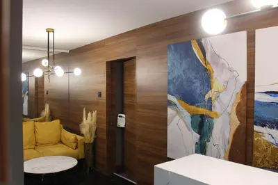 a living room with a yellow couch and a painting on the wall at Elite Space in Niš