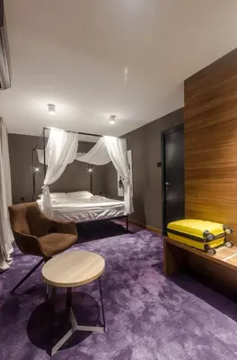 a bedroom with a bed and a chair and a table at Elite Space in Niš