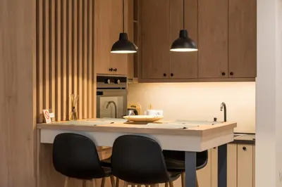 a kitchen with wooden cabinets and a island with black chairs at Apartman Sandra Free parkig in Vrnjačka Banja