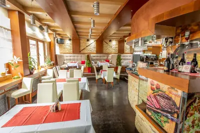 a restaurant with white tables and chairs and a bar at Zen apartman in Kopaonik