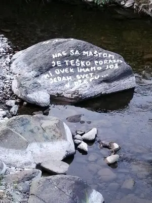 a rock with writing on it in the water at Galerija68 in Kraljevo