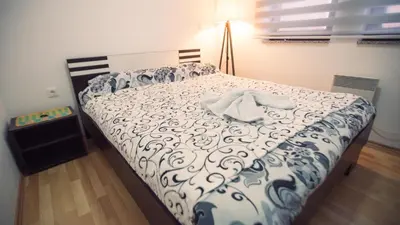 a bedroom with a bed with a white and blue comforter at Aber Apartmani Kopaonik in Kopaonik