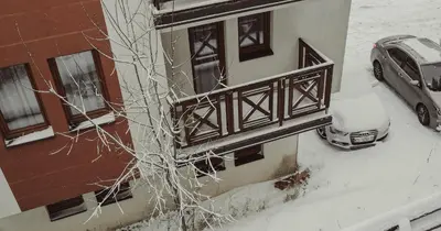 a snow covered building with a car parked next to it at Aber Apartmani Kopaonik in Kopaonik