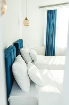 a white couch with pillows sitting next to a window at Sky apartmani & spa-Vip Lux DOO in Leskovac