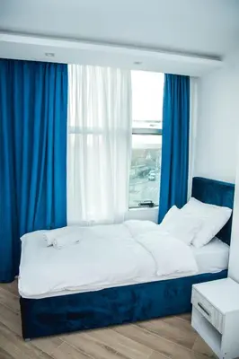 a bedroom with a bed with blue curtains and a window at Sky apartmani & spa-Vip Lux DOO in Leskovac