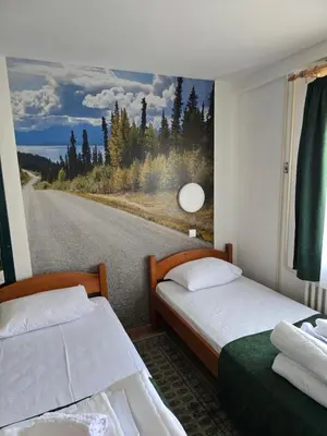 two beds in a room with a picture of a road at Studios Šumska Kuća 2 & 3 in Kopaonik