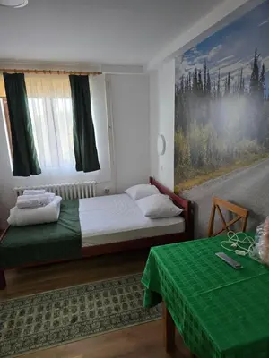 a bedroom with a bed and a painting of a road at Studios Šumska Kuća 2 & 3 in Kopaonik