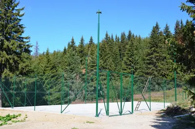 a tennis court with a fence and a net at Studios Šumska Kuća 2 & 3 in Kopaonik