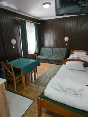 a room with two beds and a table and a couch at Studios Šumska Kuća 1 in Kopaonik